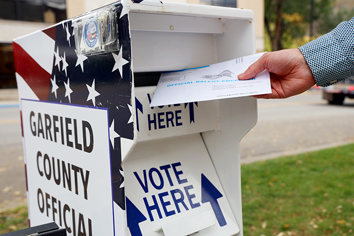 A voter drops a completed mail ballot into an official Garfield County drop box in Glenwood Springs, Colorado.